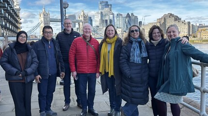 eight members of superhighways standing in front of a scenic background of tower bridge, the river thames and surrounding buildings