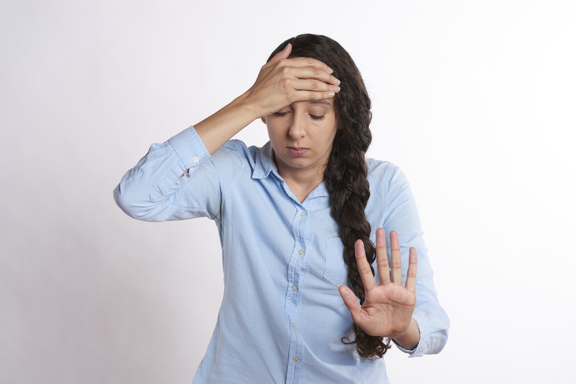 Lady with hand on head and arm outstretched saying no more