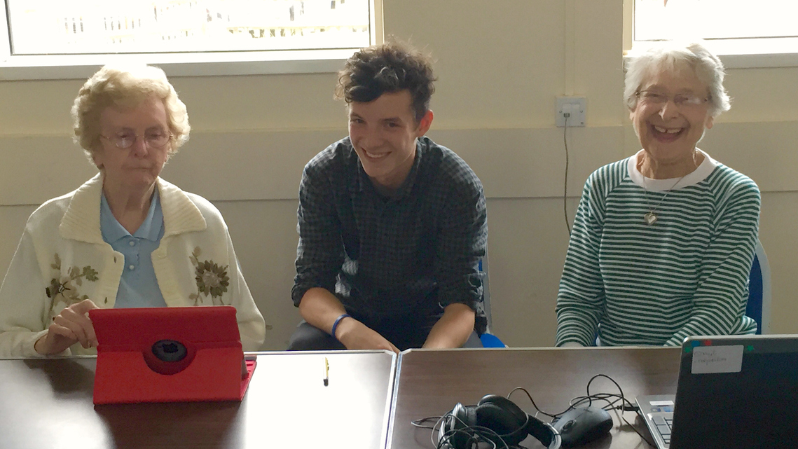 Photo of young volunteer and mature learners laughing