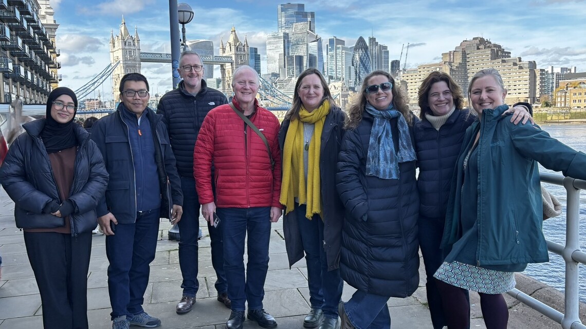 eight members of superhighways standing in front of a scenic background of tower bridge, the river thames and surrounding buildings